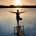 mujer frente a un lago en la puesta de sol
