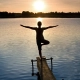 mujer frente a un lago en la puesta de sol