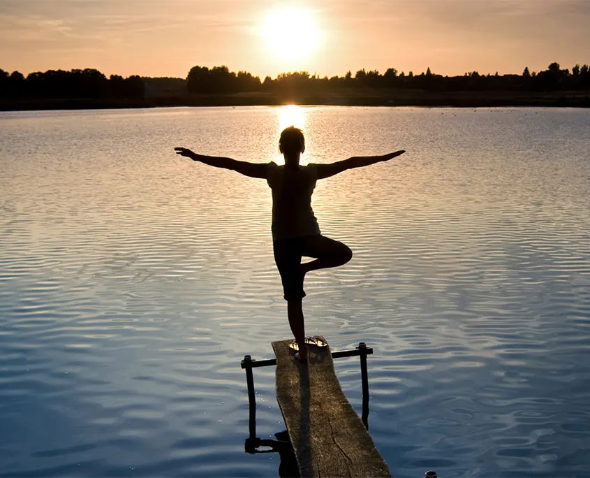 mujer frente a un lago en la puesta de sol