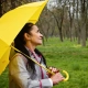 mujer con un paraguas amarillo resguardándose de la lluvia
