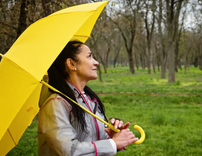 mujer con un paraguas amarillo resguardándose de la lluvia