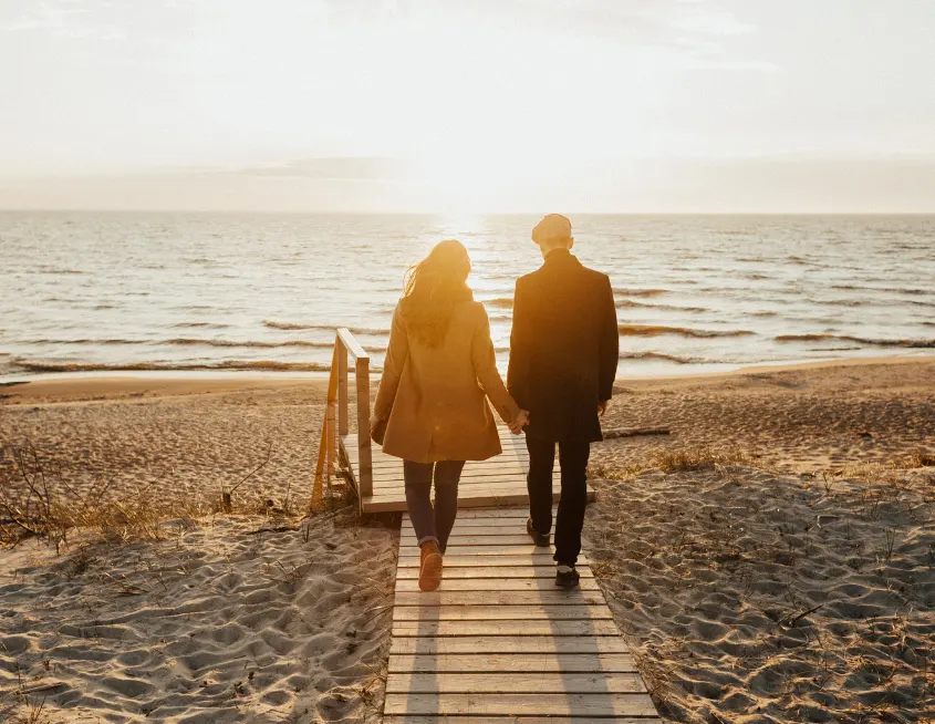pareja paseando por la playa en el atardecer