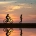 foto de gente corriendo y yendo en bicicleta por la playa con fondo de puesta de sol