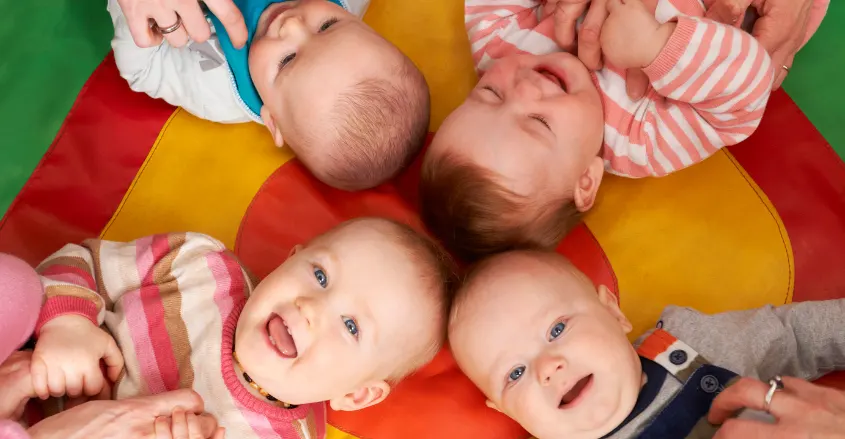 imagen de cuatro bebés contentos en la guardería jugando y riendo