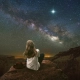 Foto de mujer sentada mirando a las estrellas en plena naturaleza