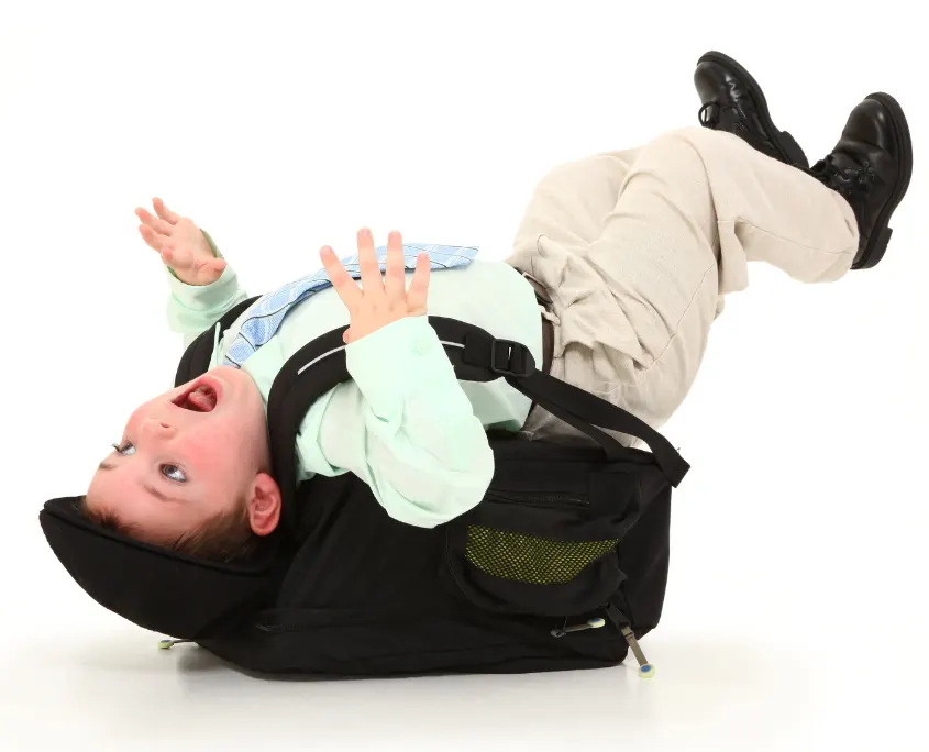 Niño que se ha caído porque le pesa demasiado la mochila para ir al colegio.
