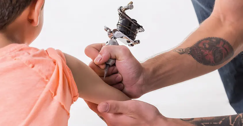 imagen de tatuador haciendo un tatuaje a un niño quiropráctico Badalona