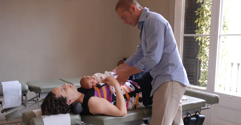 Quiropráctico atendiendo a una paciente con un bebé Barcelona